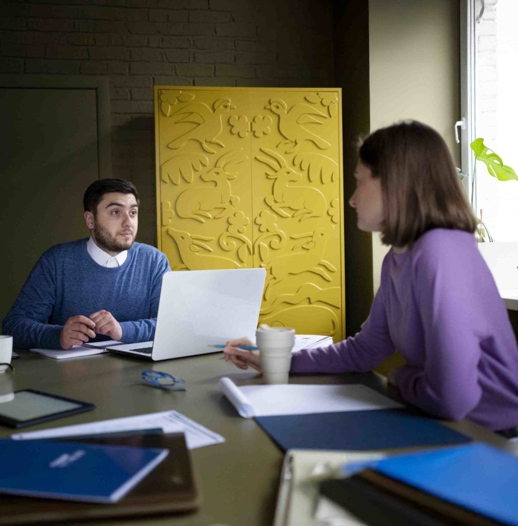 man-wearing-blue-sweater-talking-with-female-wearing-purple-tshirt-career-discussion